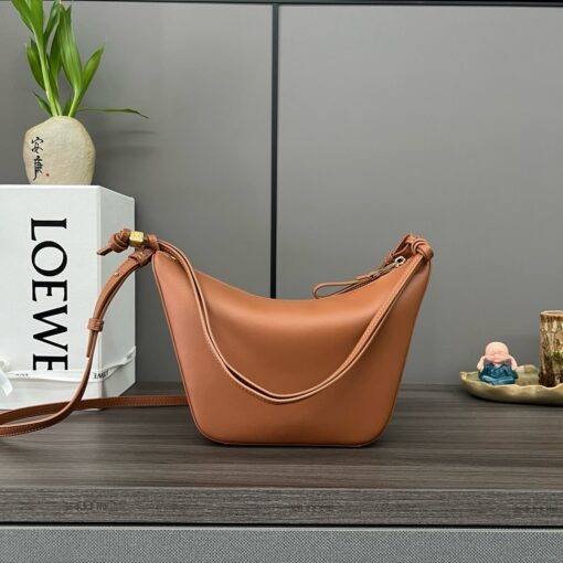 Mini Hammock Hobo. Authentic quality luxury bag crafted in genuine leather comes with authenticity card, dust bag and gift bag. Effortless Form, Everyday Function. The Mini Hammock Hobo is a contemporary reimagining of *oewe’s iconic Hammock bag. This streamlined variation offers a sleek, sculptural silhouette designed as a versatile sling bag for modern living. Expertly crafted in classic calfskin, it features soft, supple leather and a compact form that adapts effortlessly to your day. The unique design allows for multiple carry options—wear it crossbody, over the shoulder, or by hand. Elegant yet functional, this mini hobo is perfect for essentials, making it an ideal choice for both daily wear and minimalist style statements.
