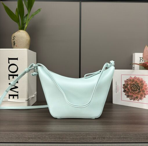 Mini Hammock Hobo. Authentic quality luxury bag crafted in genuine leather comes with authenticity card, dust bag and gift bag. Effortless Form, Everyday Function. The Mini Hammock Hobo is a contemporary reimagining of *oewe’s iconic Hammock bag. This streamlined variation offers a sleek, sculptural silhouette designed as a versatile sling bag for modern living. Expertly crafted in classic calfskin, it features soft, supple leather and a compact form that adapts effortlessly to your day. The unique design allows for multiple carry options—wear it crossbody, over the shoulder, or by hand. Elegant yet functional, this mini hobo is perfect for essentials, making it an ideal choice for both daily wear and minimalist style statements.