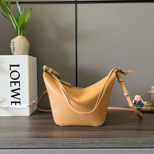 Mini Hammock Hobo. Authentic quality luxury bag crafted in genuine leather comes with authenticity card, dust bag and gift bag. Effortless Form, Everyday Function. The Mini Hammock Hobo is a contemporary reimagining of *oewe’s iconic Hammock bag. This streamlined variation offers a sleek, sculptural silhouette designed as a versatile sling bag for modern living. Expertly crafted in classic calfskin, it features soft, supple leather and a compact form that adapts effortlessly to your day. The unique design allows for multiple carry options—wear it crossbody, over the shoulder, or by hand. Elegant yet functional, this mini hobo is perfect for essentials, making it an ideal choice for both daily wear and minimalist style statements.