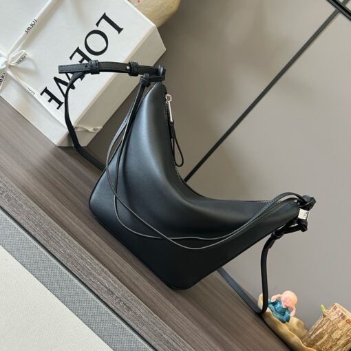 Mini Hammock Hobo. Authentic quality luxury bag crafted in genuine leather comes with authenticity card, dust bag and gift bag. Effortless Form, Everyday Function. The Mini Hammock Hobo is a contemporary reimagining of *oewe’s iconic Hammock bag. This streamlined variation offers a sleek, sculptural silhouette designed as a versatile sling bag for modern living. Expertly crafted in classic calfskin, it features soft, supple leather and a compact form that adapts effortlessly to your day. The unique design allows for multiple carry options—wear it crossbody, over the shoulder, or by hand. Elegant yet functional, this mini hobo is perfect for essentials, making it an ideal choice for both daily wear and minimalist style statements.