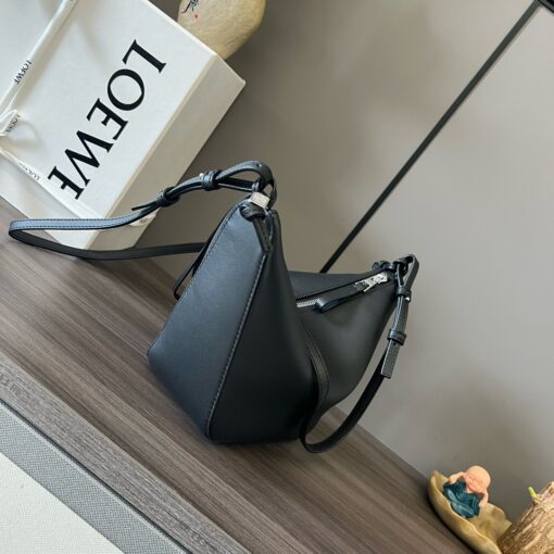 Mini Hammock Hobo. Authentic quality luxury bag crafted in genuine leather comes with authenticity card, dust bag and gift bag. Effortless Form, Everyday Function. The Mini Hammock Hobo is a contemporary reimagining of *oewe’s iconic Hammock bag. This streamlined variation offers a sleek, sculptural silhouette designed as a versatile sling bag for modern living. Expertly crafted in classic calfskin, it features soft, supple leather and a compact form that adapts effortlessly to your day. The unique design allows for multiple carry options—wear it crossbody, over the shoulder, or by hand. Elegant yet functional, this mini hobo is perfect for essentials, making it an ideal choice for both daily wear and minimalist style statements.