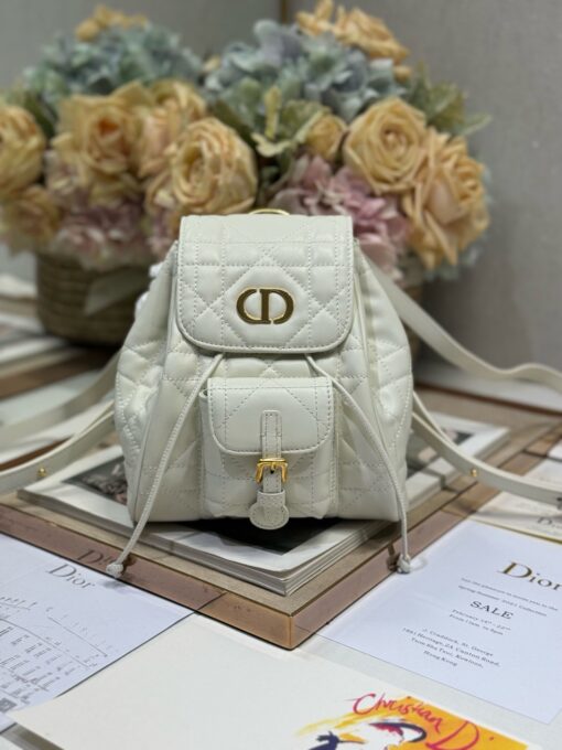 Small Caro Backpack. Authentic quality luxury bag crafted in genuine leather comes with authenticity card, dust bag and gift bag. Elegance Meets Effortless Edge. Elevate your everyday with the Small Caro Backpack — a flawless blend of modern femininity and iconic House craftsmanship. Luxuriously crafted in lambskin, its supple silhouette is enhanced by bold Macrocannage topstitching that whispers timeless *ior style. The antique gold-finish ‘CD’ clasp opens to a drawstring main compartment, perfectly balancing beauty and practicality. A discreet flap pocket keeps your daily essentials close at hand, while the top handle and adjustable leather straps offer versatile, all-day comfort. Whether slung over your shoulder or carried by hand, this petite powerhouse delivers Parisian polish in every step.