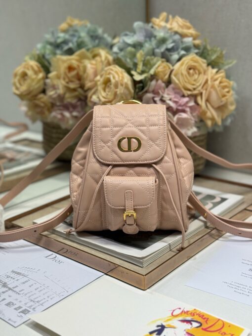 Small Caro Backpack. Authentic quality luxury bag crafted in genuine leather comes with authenticity card, dust bag and gift bag. Elegance Meets Effortless Edge. Elevate your everyday with the Small Caro Backpack — a flawless blend of modern femininity and iconic House craftsmanship. Luxuriously crafted in lambskin, its supple silhouette is enhanced by bold Macrocannage topstitching that whispers timeless *ior style. The antique gold-finish ‘CD’ clasp opens to a drawstring main compartment, perfectly balancing beauty and practicality. A discreet flap pocket keeps your daily essentials close at hand, while the top handle and adjustable leather straps offer versatile, all-day comfort. Whether slung over your shoulder or carried by hand, this petite powerhouse delivers Parisian polish in every step.