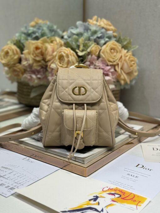 Small Caro Backpack. Authentic quality luxury bag crafted in genuine leather comes with authenticity card, dust bag and gift bag. Elegance Meets Effortless Edge. Elevate your everyday with the Small Caro Backpack — a flawless blend of modern femininity and iconic House craftsmanship. Luxuriously crafted in lambskin, its supple silhouette is enhanced by bold Macrocannage topstitching that whispers timeless *ior style. The antique gold-finish ‘CD’ clasp opens to a drawstring main compartment, perfectly balancing beauty and practicality. A discreet flap pocket keeps your daily essentials close at hand, while the top handle and adjustable leather straps offer versatile, all-day comfort. Whether slung over your shoulder or carried by hand, this petite powerhouse delivers Parisian polish in every step.