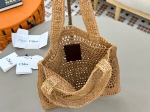 Summer Banana Tote Bag. Authentic quality luxury bag crafted in genuine leather comes with authenticity card, dust bag and gift bag. Heritage in Hand: Where Artisan Craft Meets Summer Elegance. Introducing the Summer Banana Tote—an artisanal masterpiece crafted from raffia and calfskin by a single artisan over 4.5 days in partnership with Made For A Woman. This spacious tote is adorned with a handwritten signature inspired by *loé’s rich heritage, while a playful dangling chain and delicate charms add the perfect finishing touch. A celebration of craftsmanship and effortless summer style.