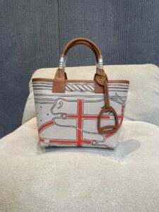 Steeple 25 Bag. Authentic quality luxury bag crafted in genuine leather comes with authenticity card, dust bag and gift bag. Where art meets heritage. The *rmès Steeple Bag is a charming fusion of heritage and artistry, crafted from a blend of canvas and Swift leather. Its design pays tribute to *rmès’ equestrian roots with whip-shaped handles and a stirrup-inspired charm, adding a playful yet sophisticated touch. Lightweight yet spacious, the Steeple is ideal for daily use. Whether you opt for a vibrant motif or a sleek, single-color design, this bag stands out as an artistic expression of luxury that seamlessly integrates into a modern lifestyle. Praised for its unique aesthetic and accessibility within the *rmès lineup, the Steeple Bag is adored by fashion enthusiasts who appreciate its colorful palette and bold personality. While it’s best suited for those who enjoy the texture and look of canvas, it remains a versatile statement piece that captures the spirit of everyday elegance. | PURSE POP UP LIVE Steeple 25 Bag. Authentic quality luxury bag crafted in genuine leather comes with authenticity card, dust bag and gift bag. Where art meets heritage. The *rmès Steeple Bag is a charming fusion of heritage and artistry, crafted from a blend of canvas and Swift leather. Its design pays tribute to *rmès’ equestrian roots with whip-shaped handles and a stirrup-inspired charm, adding a playful yet sophisticated touch. Lightweight yet spacious, the Steeple is ideal for daily use. Whether you opt for a vibrant motif or a sleek, single-color design, this bag stands out as an artistic expression of luxury that seamlessly integrates into a modern lifestyle. Praised for its unique aesthetic and accessibility within the *rmès lineup, the Steeple Bag is adored by fashion enthusiasts who appreciate its colorful palette and bold personality. While it’s best suited for those who enjoy the texture and look of canvas, it remains a versatile statement piece that captures the spirit of everyday elegance.