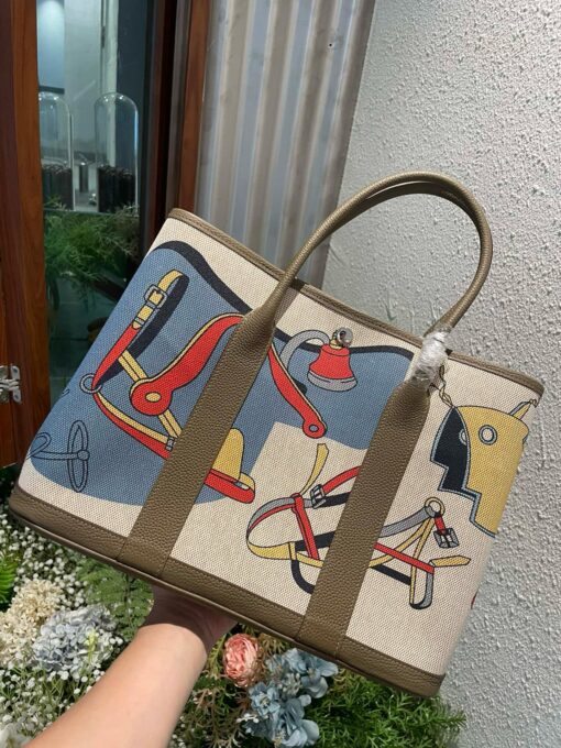 Garden Party Voyage. Authentic quality luxury bag crafted in genuine leather comes with authenticity card, dust bag and gift bag. The Art of Everyday Escape. Chic, structured, and effortlessly refined, the *RMÈS Garden Party Voyage is the perfect companion for your daily adventures or spontaneous weekend getaways. Crafted with precision in supple Negonda leather or canvas with leather trim, this midsize tote strikes the perfect balance between luxury and functionality. Its minimalist silhouette is elevated by discreet Clou de Selle snap closures and expandable sides, offering both form and flexibility. Spacious enough for your essentials yet compact enough to carry with ease, it’s a timeless piece designed to move with you—gracefully. Whether carried in hand or worn over the shoulder, the Garden Party Voyage 36 speaks in whispers of elegance and unmistakable *RMÈS craftsmanship. Every day is a journey. Travel beautifully.