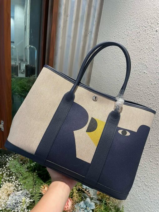 Garden Party Voyage. Authentic quality luxury bag crafted in genuine leather comes with authenticity card, dust bag and gift bag. The Art of Everyday Escape. Chic, structured, and effortlessly refined, the *RMÈS Garden Party Voyage is the perfect companion for your daily adventures or spontaneous weekend getaways. Crafted with precision in supple Negonda leather or canvas with leather trim, this midsize tote strikes the perfect balance between luxury and functionality. Its minimalist silhouette is elevated by discreet Clou de Selle snap closures and expandable sides, offering both form and flexibility. Spacious enough for your essentials yet compact enough to carry with ease, it’s a timeless piece designed to move with you—gracefully. Whether carried in hand or worn over the shoulder, the Garden Party Voyage 36 speaks in whispers of elegance and unmistakable *RMÈS craftsmanship. Every day is a journey. Travel beautifully.