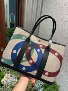 Garden Party Voyage. Authentic quality luxury bag crafted in genuine leather comes with authenticity card, dust bag and gift bag. The Art of Everyday Escape. Chic, structured, and effortlessly refined, the *RMÈS Garden Party Voyage is the perfect companion for your daily adventures or spontaneous weekend getaways. Crafted with precision in supple Negonda leather or canvas with leather trim, this midsize tote strikes the perfect balance between luxury and functionality. Its minimalist silhouette is elevated by discreet Clou de Selle snap closures and expandable sides, offering both form and flexibility. Spacious enough for your essentials yet compact enough to carry with ease, it’s a timeless piece designed to move with you—gracefully. Whether carried in hand or worn over the shoulder, the Garden Party Voyage 36 speaks in whispers of elegance and unmistakable *RMÈS craftsmanship. Every day is a journey. Travel beautifully.