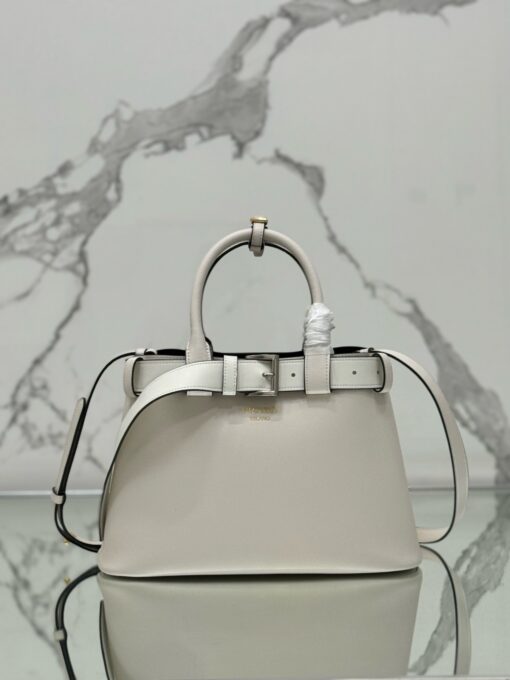 Buckle Small Leather Handbag. Authentic quality luxury bag crafted in genuine leather comes with authenticity card, dust bag and gift bag. Sophistication Meets Utility. Sleek, structured, and undeniably Pr*da — the Buckle Small Leather Handbag captures the brand’s signature balance of minimalist elegance and refined detail. Crafted in smooth leather with a buttery-soft nappa interior, this compact piece is a masterclass in functional luxury. A standout feature? Its interchangeable belt strap, adding a bold, modern twist to the timeless silhouette. Whether you're heading to a meeting or a soirée, this bag adapts seamlessly to your mood and moment. Finished with the embossed iconic logo, it’s a quiet statement of taste and distinction. A versatile companion for the woman who appreciates precision, polish, and just the right touch of edge.