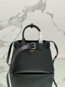 Buckle Small Leather Handbag. Authentic quality luxury bag crafted in genuine leather comes with authenticity card, dust bag and gift bag. Sophistication Meets Utility. Sleek, structured, and undeniably Pr*da — the Buckle Small Leather Handbag captures the brand’s signature balance of minimalist elegance and refined detail. Crafted in smooth leather with a buttery-soft nappa interior, this compact piece is a masterclass in functional luxury. A standout feature? Its interchangeable belt strap, adding a bold, modern twist to the timeless silhouette. Whether you're heading to a meeting or a soirée, this bag adapts seamlessly to your mood and moment. Finished with the embossed iconic logo, it’s a quiet statement of taste and distinction. A versatile companion for the woman who appreciates precision, polish, and just the right touch of edge.