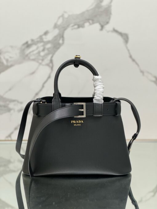 Buckle Small Leather Handbag. Authentic quality luxury bag crafted in genuine leather comes with authenticity card, dust bag and gift bag. Sophistication Meets Utility. Sleek, structured, and undeniably Pr*da — the Buckle Small Leather Handbag captures the brand’s signature balance of minimalist elegance and refined detail. Crafted in smooth leather with a buttery-soft nappa interior, this compact piece is a masterclass in functional luxury. A standout feature? Its interchangeable belt strap, adding a bold, modern twist to the timeless silhouette. Whether you're heading to a meeting or a soirée, this bag adapts seamlessly to your mood and moment. Finished with the embossed iconic logo, it’s a quiet statement of taste and distinction. A versatile companion for the woman who appreciates precision, polish, and just the right touch of edge.
