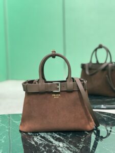 Buckle Small Leather Handbag. Authentic quality luxury bag crafted in genuine leather comes with authenticity card, dust bag and gift bag. Sophistication Meets Utility. Sleek, structured, and undeniably Pr*da — the Buckle Small Leather Handbag captures the brand’s signature balance of minimalist elegance and refined detail. Crafted in smooth leather with a buttery-soft nappa interior, this compact piece is a masterclass in functional luxury. A standout feature? Its interchangeable belt strap, adding a bold, modern twist to the timeless silhouette. Whether you're heading to a meeting or a soirée, this bag adapts seamlessly to your mood and moment. Finished with the embossed iconic logo, it’s a quiet statement of taste and distinction. A versatile companion for the woman who appreciates precision, polish, and just the right touch of edge.