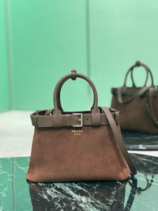 Buckle Small Leather Handbag. Authentic quality luxury bag crafted in genuine leather comes with authenticity card, dust bag and gift bag. Sophistication Meets Utility. Sleek, structured, and undeniably Pr*da — the Buckle Small Leather Handbag captures the brand’s signature balance of minimalist elegance and refined detail. Crafted in smooth leather with a buttery-soft nappa interior, this compact piece is a masterclass in functional luxury. A standout feature? Its interchangeable belt strap, adding a bold, modern twist to the timeless silhouette. Whether you're heading to a meeting or a soirée, this bag adapts seamlessly to your mood and moment. Finished with the embossed iconic logo, it’s a quiet statement of taste and distinction. A versatile companion for the woman who appreciates precision, polish, and just the right touch of edge.
