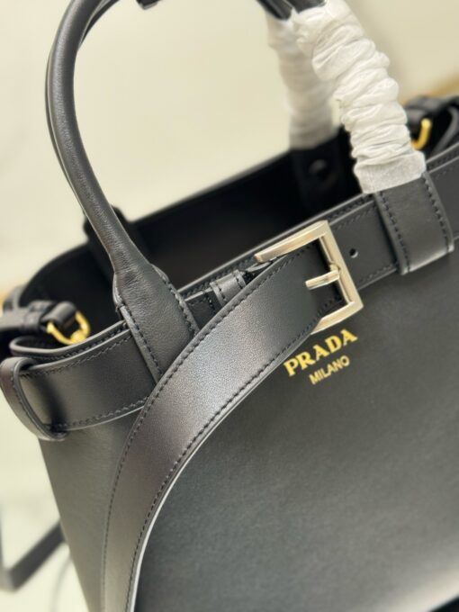 Buckle Small Leather Handbag. Authentic quality luxury bag crafted in genuine leather comes with authenticity card, dust bag and gift bag. Sophistication Meets Utility. Sleek, structured, and undeniably Pr*da — the Buckle Small Leather Handbag captures the brand’s signature balance of minimalist elegance and refined detail. Crafted in smooth leather with a buttery-soft nappa interior, this compact piece is a masterclass in functional luxury. A standout feature? Its interchangeable belt strap, adding a bold, modern twist to the timeless silhouette. Whether you're heading to a meeting or a soirée, this bag adapts seamlessly to your mood and moment. Finished with the embossed iconic logo, it’s a quiet statement of taste and distinction. A versatile companion for the woman who appreciates precision, polish, and just the right touch of edge.