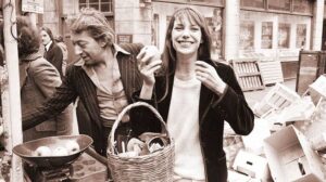 Jane Birkin seated in a cafe with her straw basket on the floor