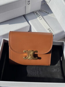 Small Flap Wallet Triomphe. Authentic quality luxury bag crafted in genuine leather comes with authenticity card, dust bag and gift bag. Small in Size, Grand in Style. Discover timeless sophistication in the palm of your hand with the *ELINE Small Flap Wallet TRIOMPHE in shiny calfskin. Meticulously crafted from luxurious leather, this compact beauty showcases the iconic Triomphe clasp in gold-tone metal, a refined nod to Parisian heritage. Despite its petite size, it opens to reveal smart compartments for cards, bills, and coins—proving that style never compromises function. Whether tucked into your favorite designer bag or carried solo for a night out, this wallet is your everyday dose of quiet luxury.
