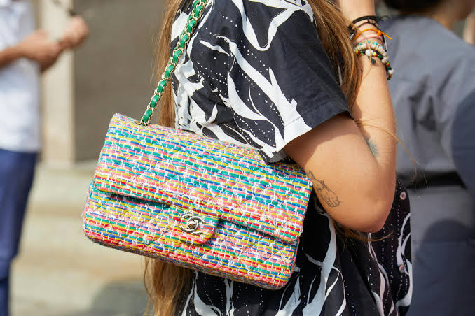 A street-style moment featuring a colorful Chanel tweed flap bag — a vibrant twist on the classic silhouette.
