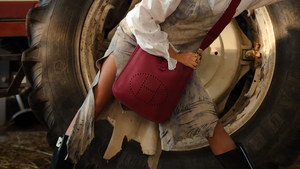 A rustic chic look with a red leather bag and a striking backdrop of a tractor tire.