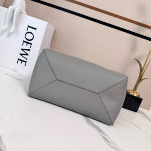 Medium Puzzle Fold Tote.  Authentic quality luxury bag crafted in genuine leather comes with authenticity card, dust bag and gift bag. Modern art meets effortless luxury. This exceptional piece reimagines the iconic Puzzle Fold silhouette with a lightweight geometric structure that folds completely flat, making it the ultimate travel companion. Crafted in supple nappa calfskin, the tote features exquisite leather marquetry squares inspired by Josef Albers’s celebrated Homage to the Square series. Each panel reflects precision, balance, and *OEWE’s unmatched craftsmanship, transforming a functional tote into a wearable work of art. Part of the exclusive *OEWE x Albers collection, this medium Puzzle Fold tote blends practicality with cultural sophistication, offering spacious elegance for everyday moments, weekend escapes, and artful adventures. A collectible masterpiece—crafted for the modern collector.