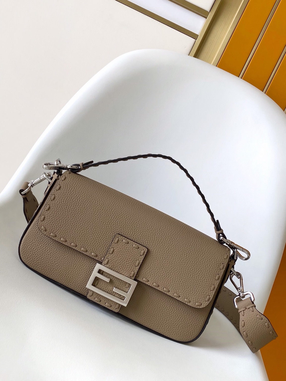 Baguette Medium 2 Baguette Medium. Authentic quality luxury bag crafted in genuine leather comes with authenticity card, dust bag and gift bag. A Legacy in Every Stitch. An icon, reimagined with artisanal mastery—the *ENDI Medium Baguette is a tribute to heritage and timeless design. Crafted in rich cappuccino Cuoio Romano leather, this piece features 612 hand-sewn tone-on-tone macro topstitches, showcasing the legendary Selleria craftsmanship passed down since 1925. Its structured silhouette is elevated by the signature FF clasp, while the soft calfskin interior, complete with a zip pocket, keeps essentials elegantly organized. Finished with a silver Selleria plaque and palladium-finish hardware, every detail speaks of quiet luxury. Versatility meets sophistication with a detachable handle and shoulder strap, allowing it to be carried by hand, worn on the shoulder, or styled cross-body. A true icon—crafted by hand, designed to last a lifetime.