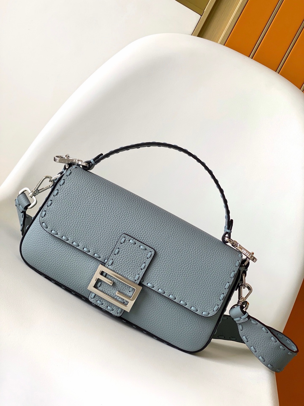 Baguette Medium 14 Baguette Medium. Authentic quality luxury bag crafted in genuine leather comes with authenticity card, dust bag and gift bag. A Legacy in Every Stitch. An icon, reimagined with artisanal mastery—the *ENDI Medium Baguette is a tribute to heritage and timeless design. Crafted in rich cappuccino Cuoio Romano leather, this piece features 612 hand-sewn tone-on-tone macro topstitches, showcasing the legendary Selleria craftsmanship passed down since 1925. Its structured silhouette is elevated by the signature FF clasp, while the soft calfskin interior, complete with a zip pocket, keeps essentials elegantly organized. Finished with a silver Selleria plaque and palladium-finish hardware, every detail speaks of quiet luxury. Versatility meets sophistication with a detachable handle and shoulder strap, allowing it to be carried by hand, worn on the shoulder, or styled cross-body. A true icon—crafted by hand, designed to last a lifetime.