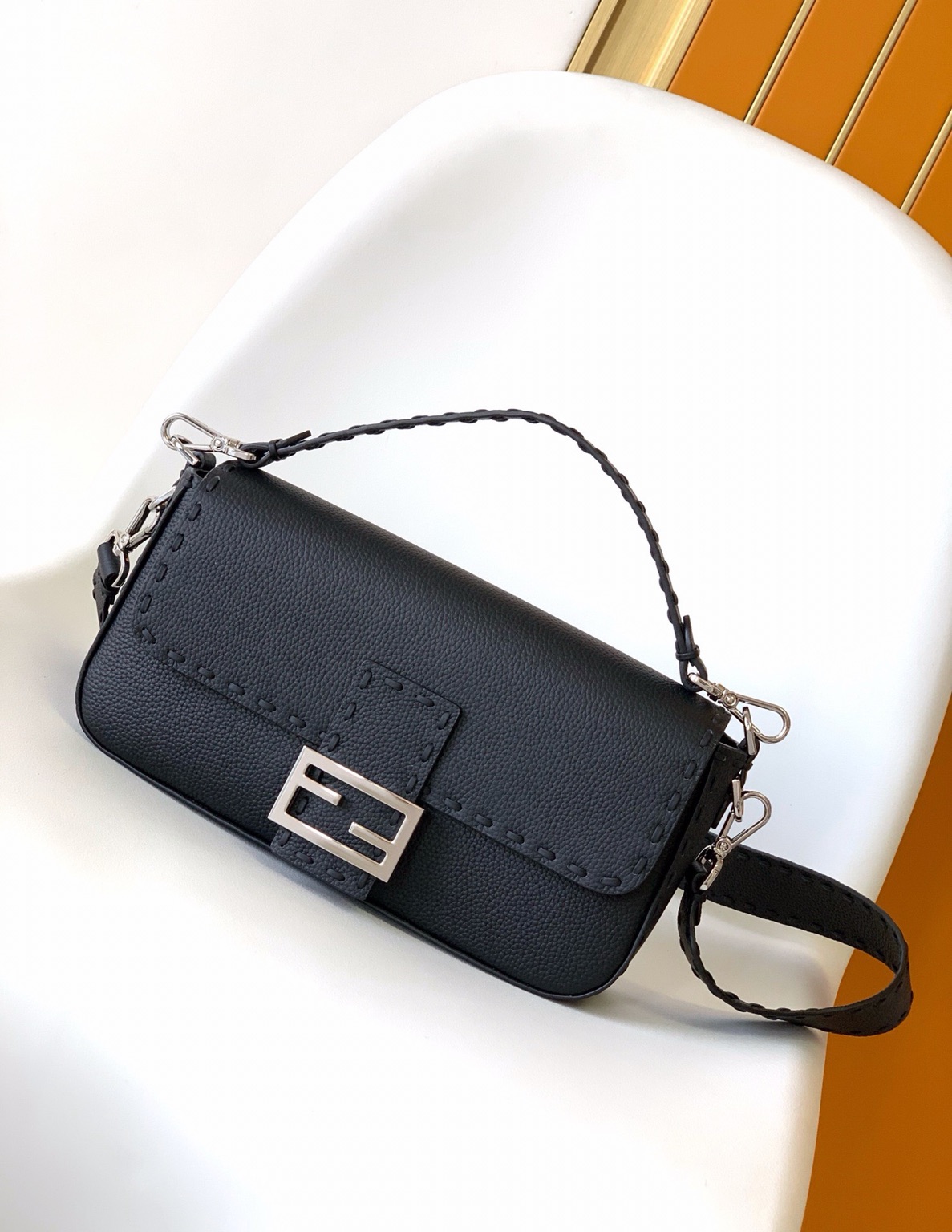 Baguette Medium 12 Baguette Medium. Authentic quality luxury bag crafted in genuine leather comes with authenticity card, dust bag and gift bag. A Legacy in Every Stitch. An icon, reimagined with artisanal mastery—the *ENDI Medium Baguette is a tribute to heritage and timeless design. Crafted in rich cappuccino Cuoio Romano leather, this piece features 612 hand-sewn tone-on-tone macro topstitches, showcasing the legendary Selleria craftsmanship passed down since 1925. Its structured silhouette is elevated by the signature FF clasp, while the soft calfskin interior, complete with a zip pocket, keeps essentials elegantly organized. Finished with a silver Selleria plaque and palladium-finish hardware, every detail speaks of quiet luxury. Versatility meets sophistication with a detachable handle and shoulder strap, allowing it to be carried by hand, worn on the shoulder, or styled cross-body. A true icon—crafted by hand, designed to last a lifetime.