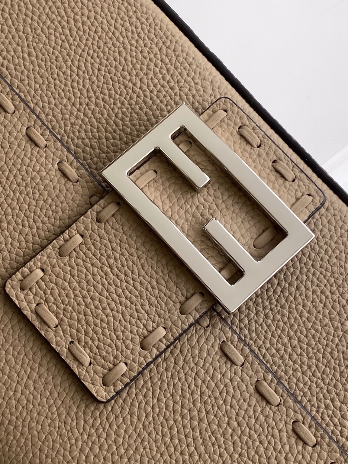 Baguette Medium 7 Baguette Medium. Authentic quality luxury bag crafted in genuine leather comes with authenticity card, dust bag and gift bag. A Legacy in Every Stitch. An icon, reimagined with artisanal mastery—the *ENDI Medium Baguette is a tribute to heritage and timeless design. Crafted in rich cappuccino Cuoio Romano leather, this piece features 612 hand-sewn tone-on-tone macro topstitches, showcasing the legendary Selleria craftsmanship passed down since 1925. Its structured silhouette is elevated by the signature FF clasp, while the soft calfskin interior, complete with a zip pocket, keeps essentials elegantly organized. Finished with a silver Selleria plaque and palladium-finish hardware, every detail speaks of quiet luxury. Versatility meets sophistication with a detachable handle and shoulder strap, allowing it to be carried by hand, worn on the shoulder, or styled cross-body. A true icon—crafted by hand, designed to last a lifetime.