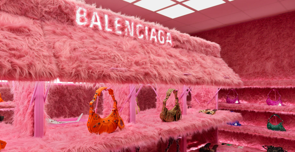 Balenciaga pop-up store covered in pink faux fur, displaying colorful handbags.